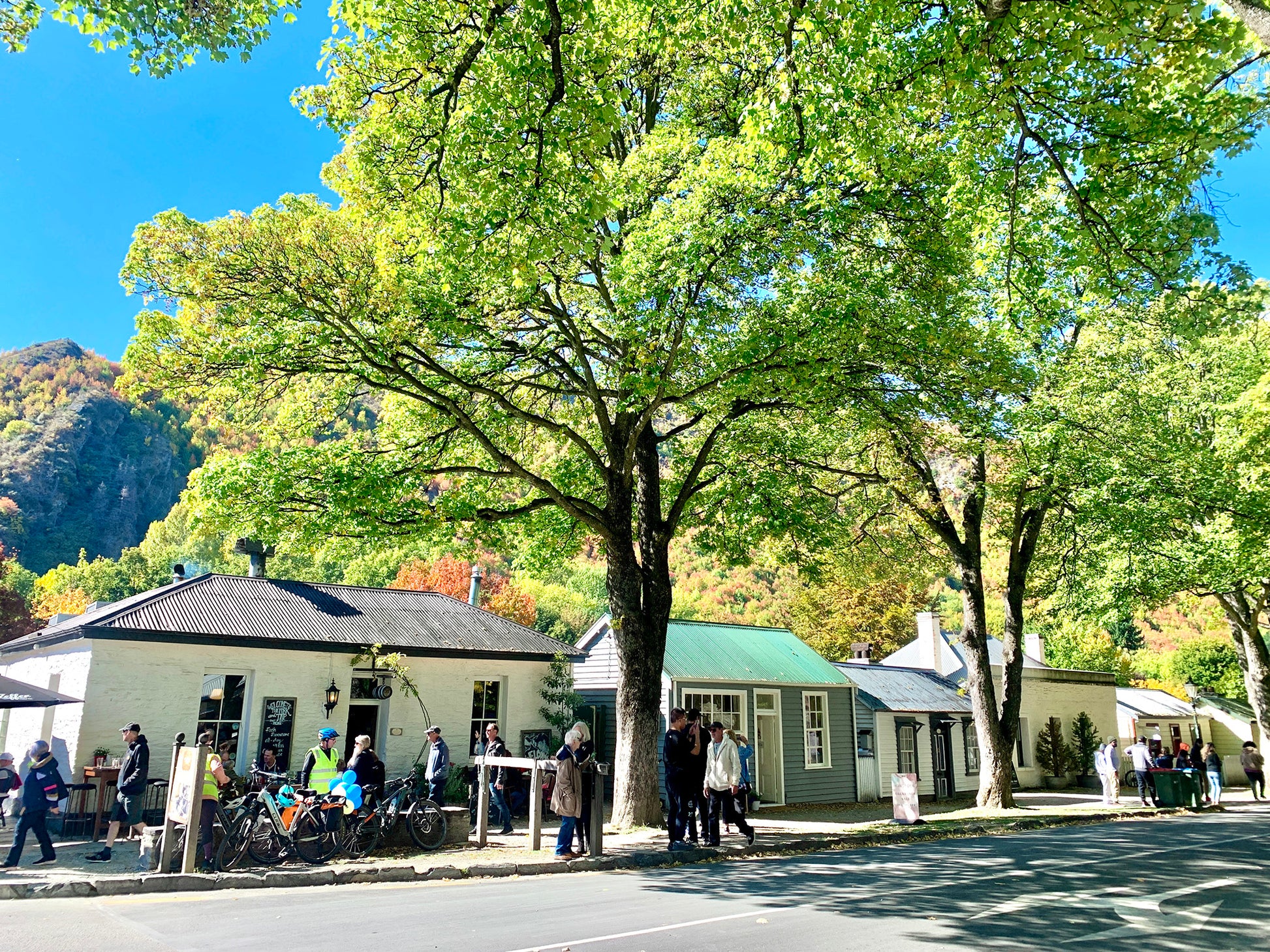 Outdoor dining and cafes in Arrowtown town centre under leafy green trees