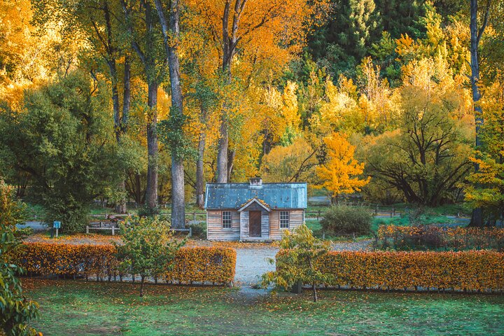 Historic stone miner’s cottage in Arrowtown surrounded by golden autumn trees
